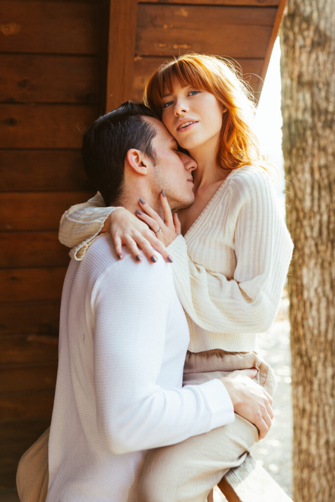 Image of couple embracing outside of Arkansas cabin during engagement photo session.